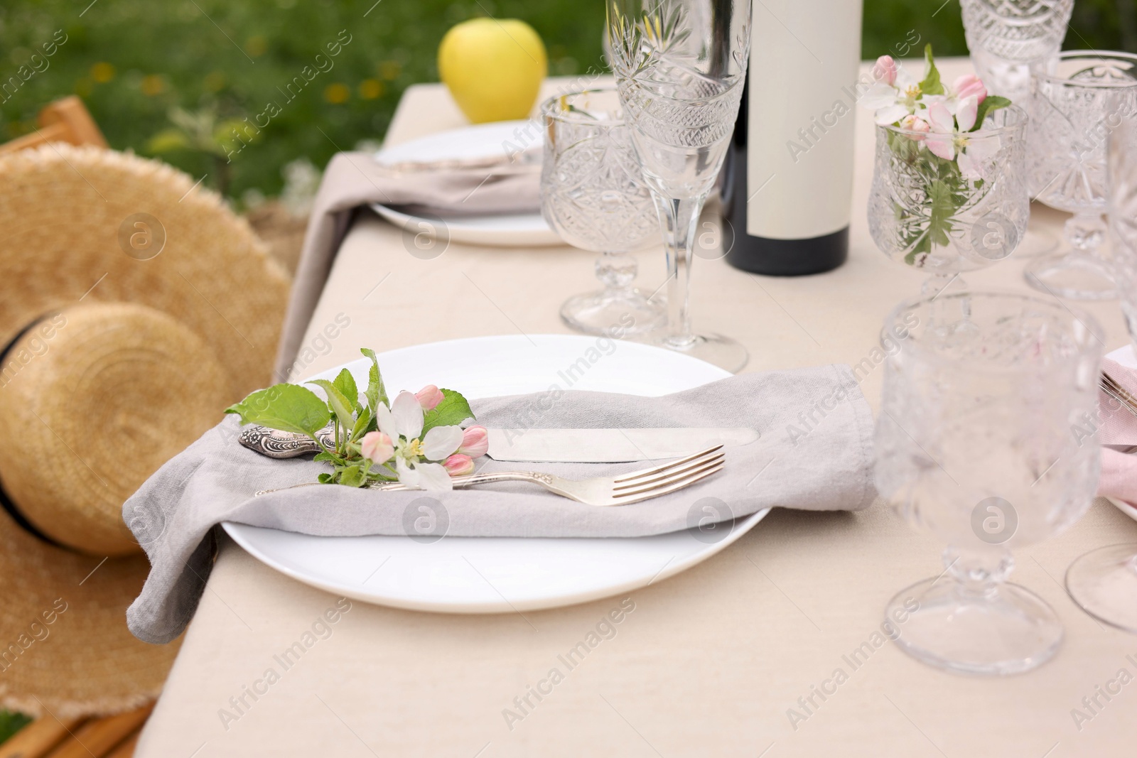 Photo of Stylish table setting with beautiful spring flowers, wine, plates and glasses in garden