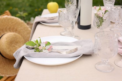 Stylish table setting with beautiful spring flowers, wine, plates and glasses in garden