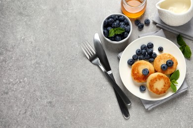 Photo of Delicious cottage cheese pancakes with blueberries, mint and honey on light grey table, flat lay. Space for text