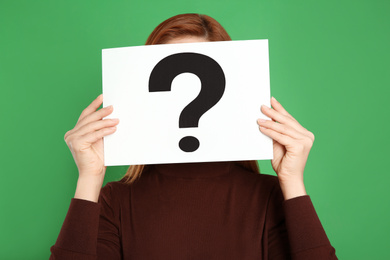 Photo of Woman holding question mark sign on green background