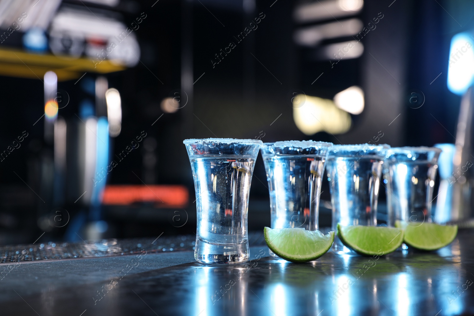 Photo of Mexican Tequila shots and lime slices on bar counter. Space for text