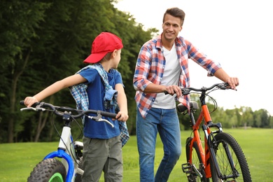 Photo of Dad and son with modern bicycles outdoors