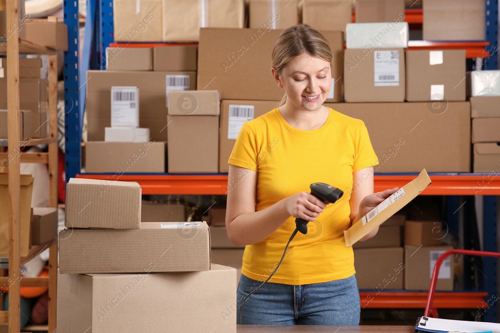 Photo of Post office worker with scanner reading parcel barcode indoors