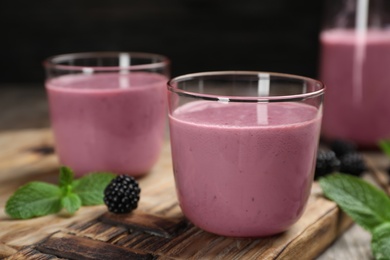 Photo of Glasses with blackberry yogurt smoothies on wooden board