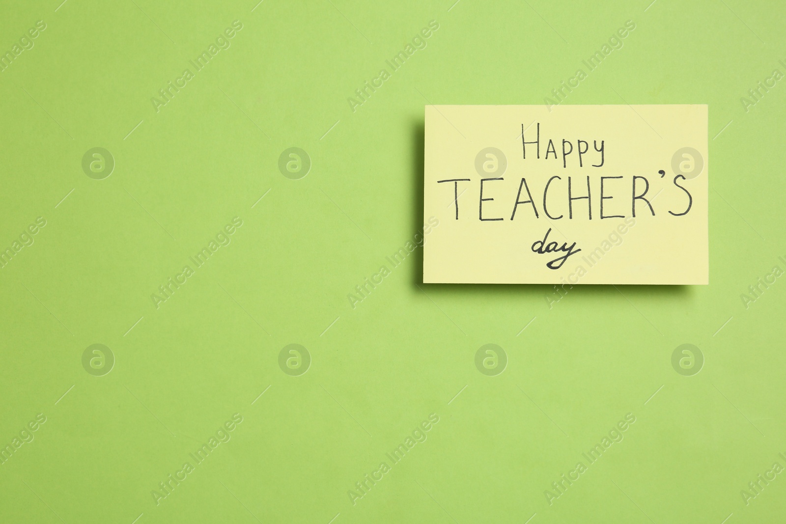 Photo of Paper with inscription HAPPY TEACHER'S DAY on light green background, top view. Space for text