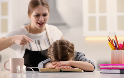 Photo of Mother scolding her daughter while helping with homework in kitchen