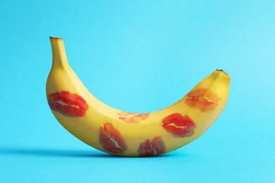 Photo of Banana covered with red lipstick marks on light blue background. Potency concept