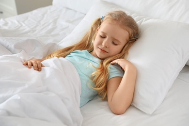 Photo of Portrait of cute little girl sleeping in large bed