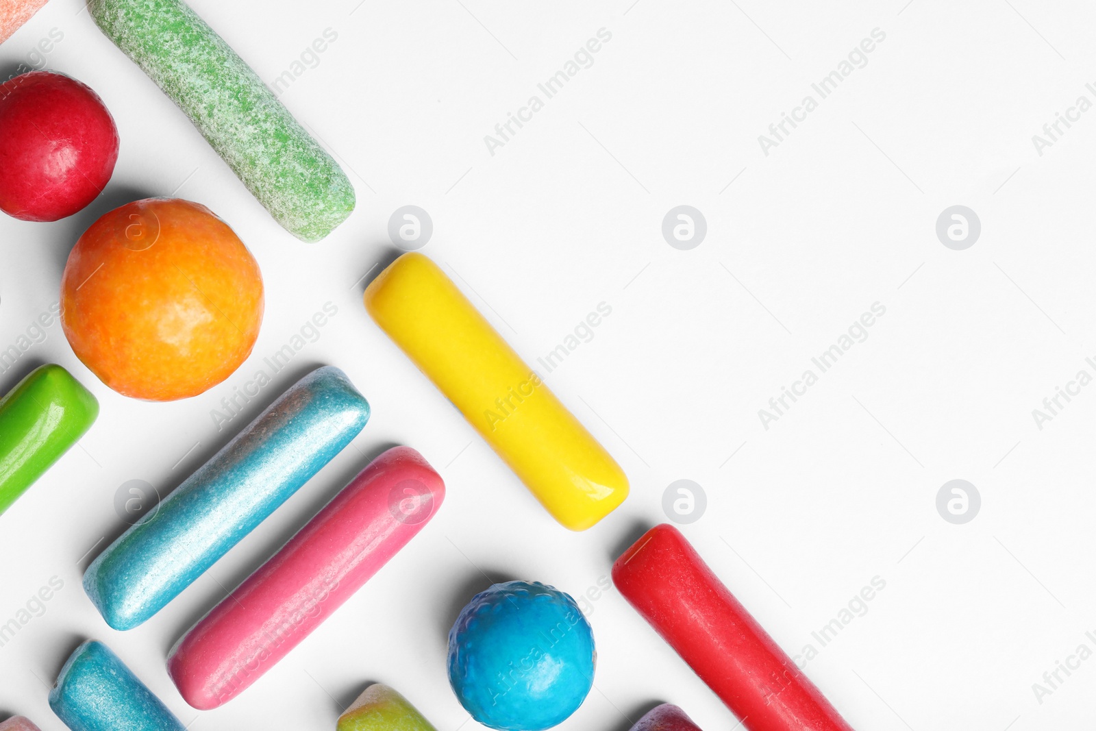 Photo of Many tasty bubble gums on white background, flat lay. Space for text