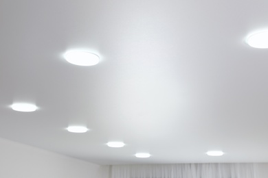 Photo of White ceiling with lamps indoors, below view