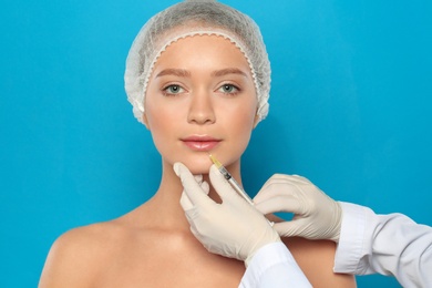 Young woman getting lips injection on color background. Cosmetic surgery