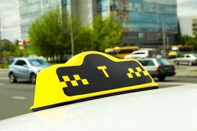 Taxi sign on car roof in city, closeup view