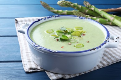 Photo of Delicious asparagus soup on blue wooden table, closeup