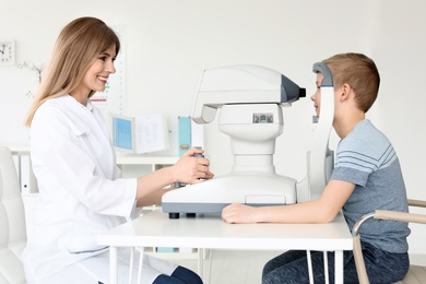 Photo of Ophthalmologist examining little boy in clinic