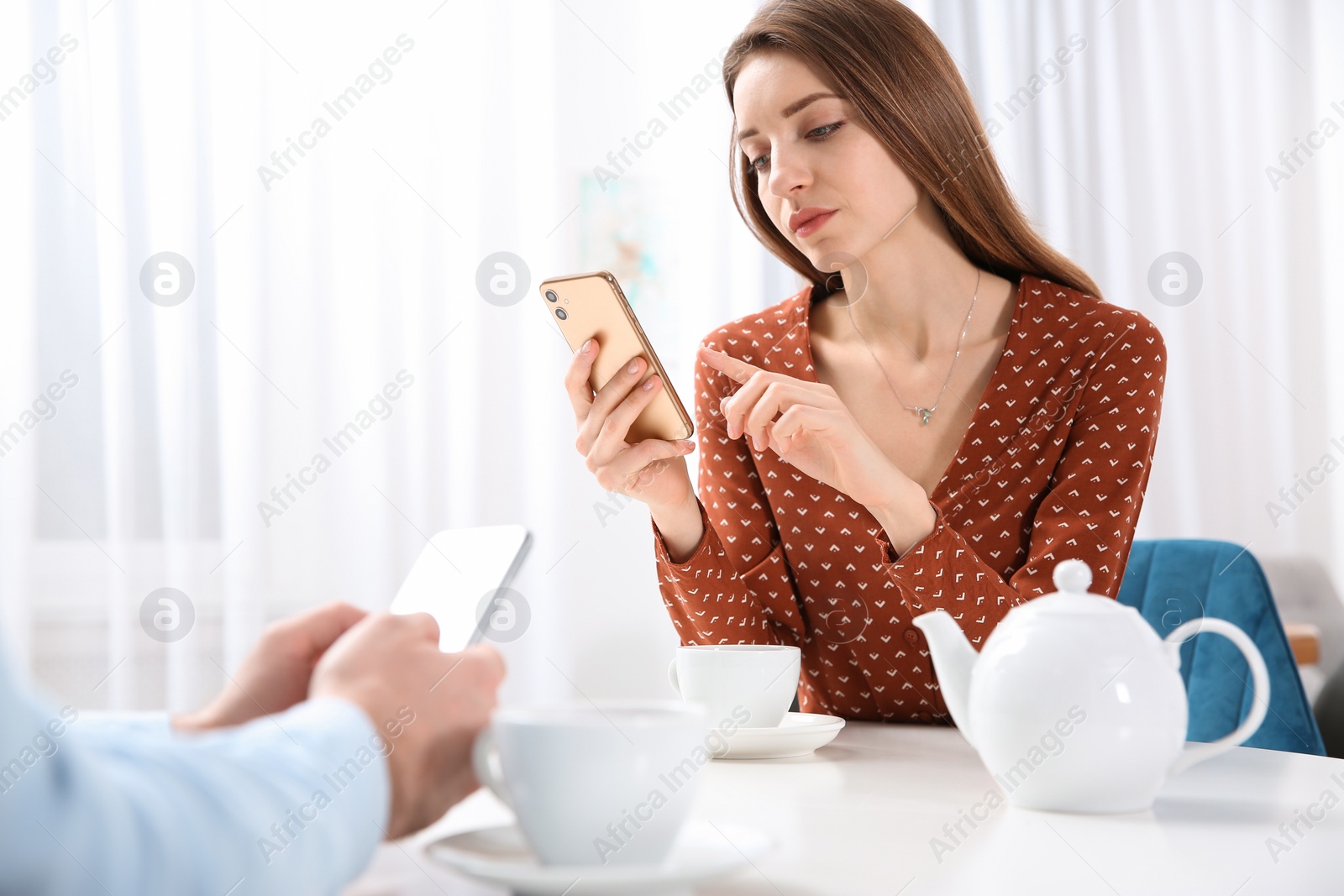 Photo of Couple addicted to smartphones ignoring each other in cafe. Relationship problems