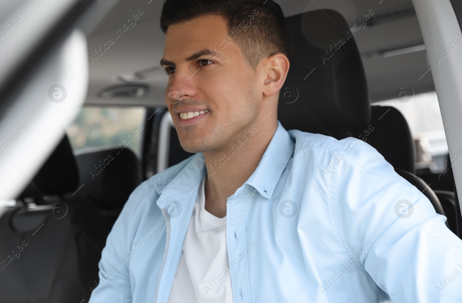 Photo of Handsome man driving his modern car, closeup