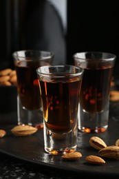 Photo of Glasses with tasty amaretto liqueur and almonds served on table, closeup