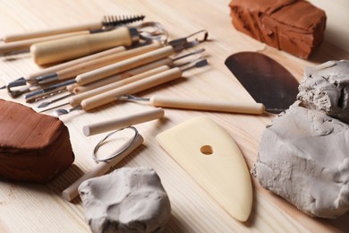 Clay and set of modeling tools on wooden table, closeup