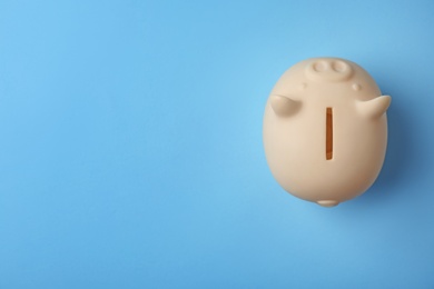 Cute piggy bank on color background, top view