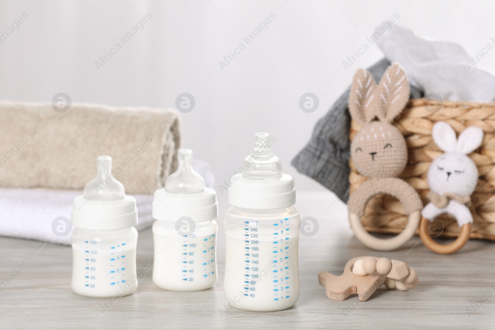 Photo of Feeding bottles with milk and baby accessories on white wooden table