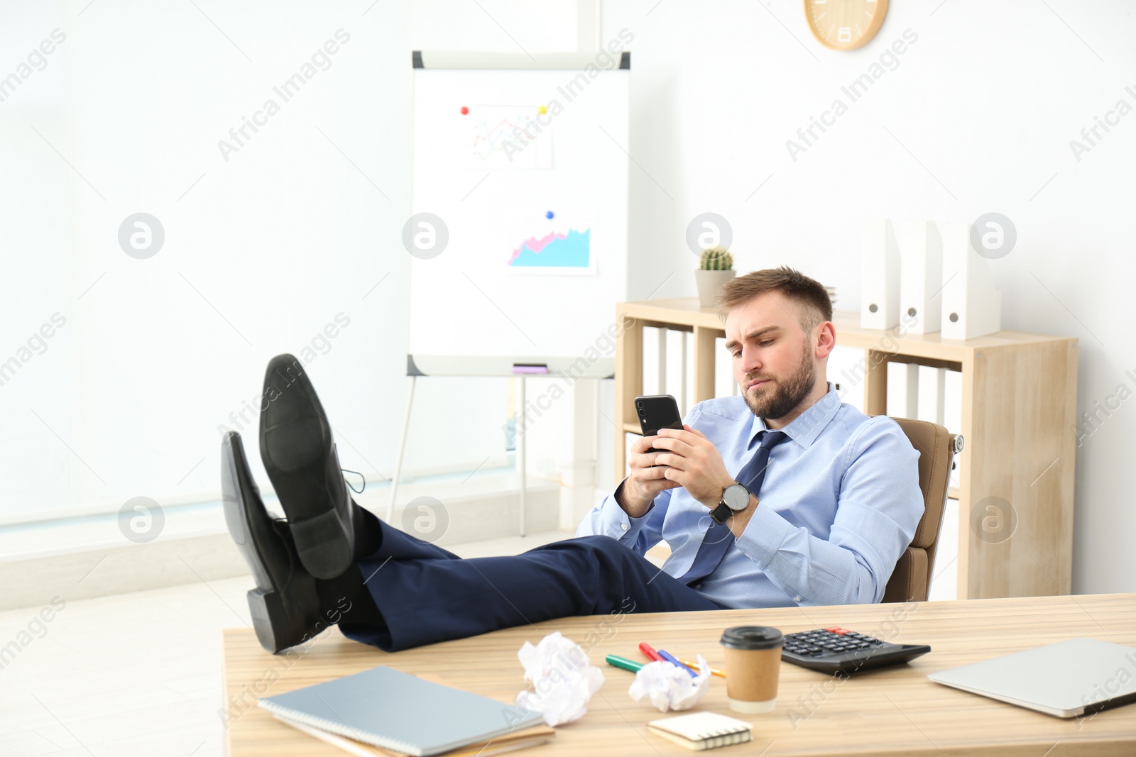 Photo of Lazy office employee with mobile phone at workplace