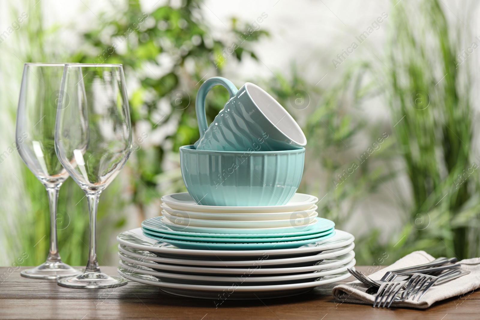 Photo of Beautiful ceramic dishware, glasses, cutlery and cup on wooden table outdoors