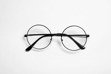 Stylish pair of glasses with black frame on white background, top view