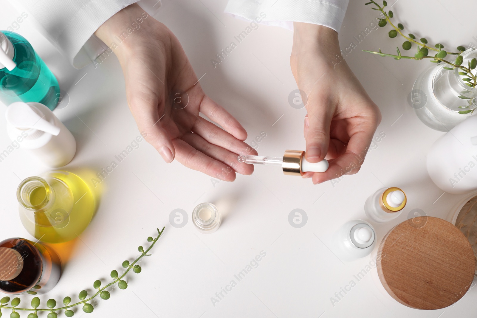 Photo of Dermatologist testing essential oil at white table, top view