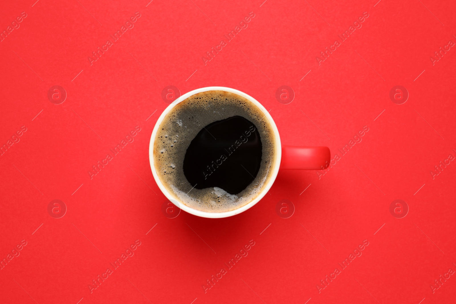 Photo of Cup of aromatic coffee on red background, top view