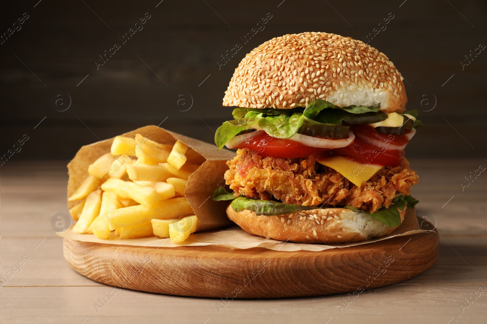 Photo of Delicious burger with crispy chicken patty and french fries on wooden table