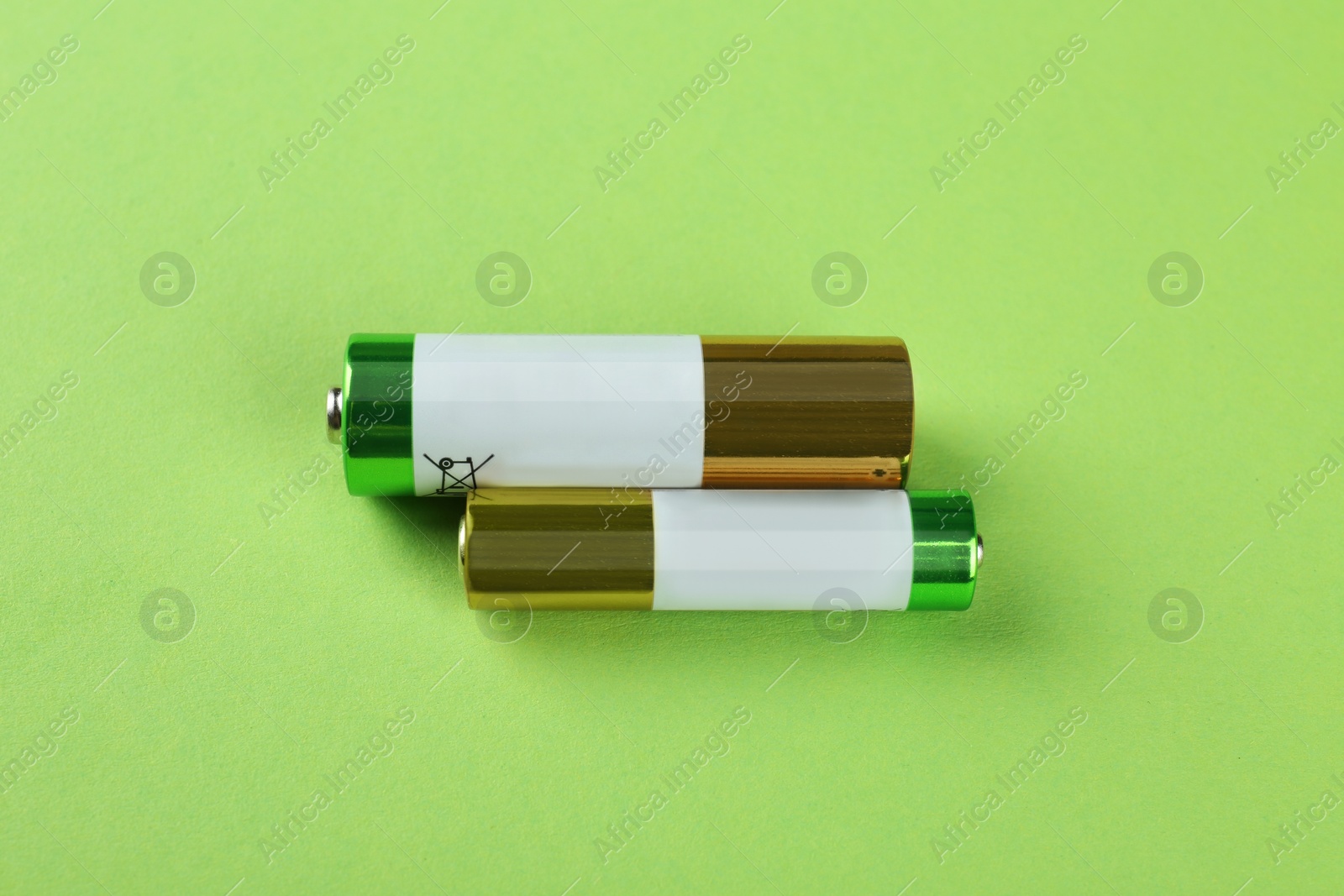 Image of Different batteries on light green background, flat lay