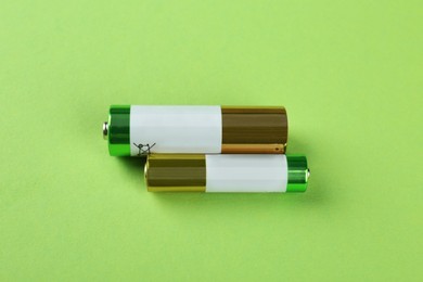 Different batteries on light green background, flat lay