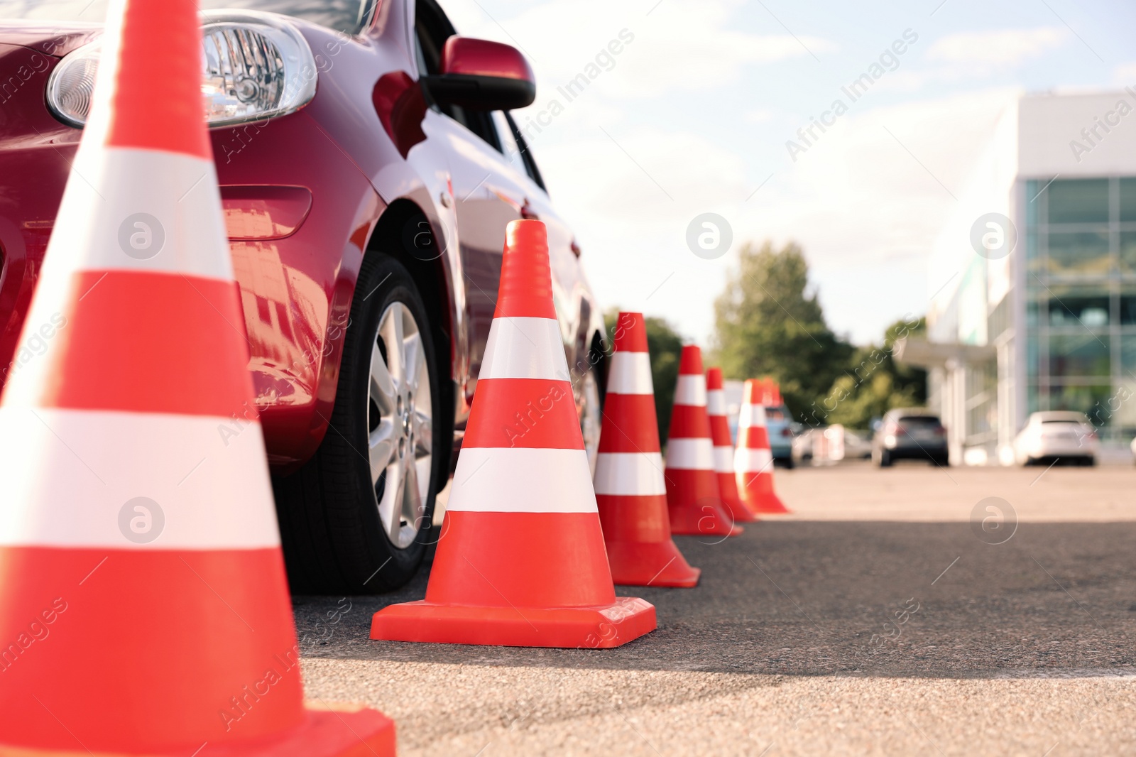 Photo of Traffic cones near red car outdoors. Driving school exam