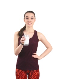 Beautiful young woman in sportswear drinking milk on white background