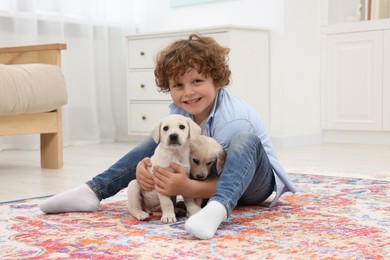 Little boy with cute puppies on carpet at home