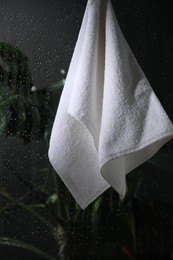 White terry towel hanging on wet glass wall in shower