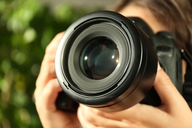 Female photographer with professional camera on blurred background, closeup