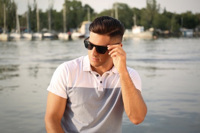 Photo of Handsome man wearing stylish sunglasses near river