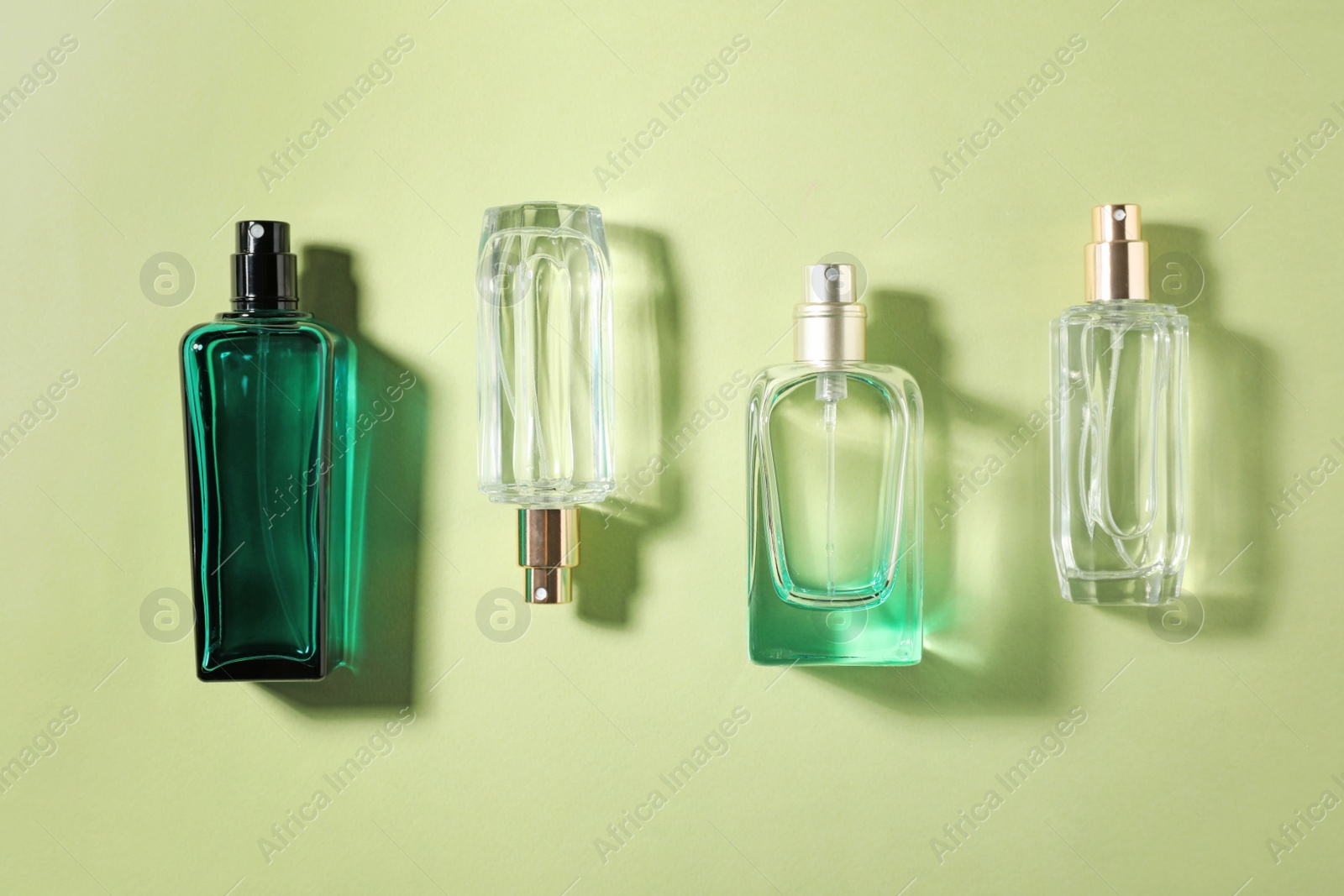 Photo of Bottles of perfume on color background, top view