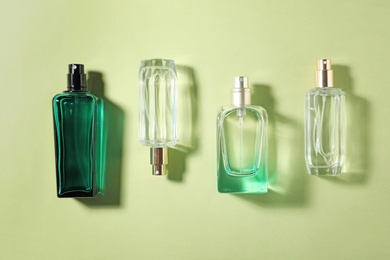 Photo of Bottles of perfume on color background, top view