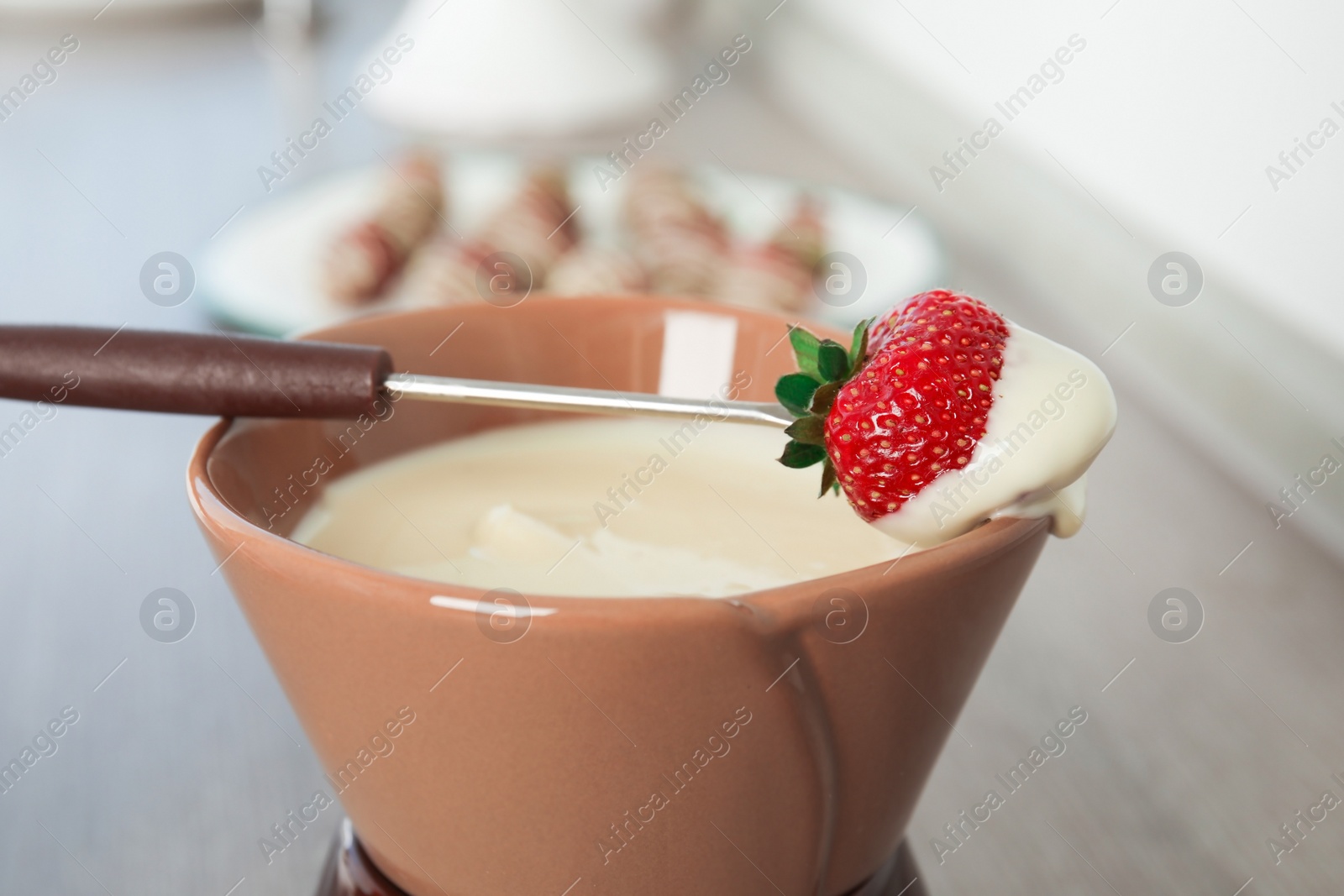 Photo of Ripe strawberry dipped into white chocolate fondue, closeup