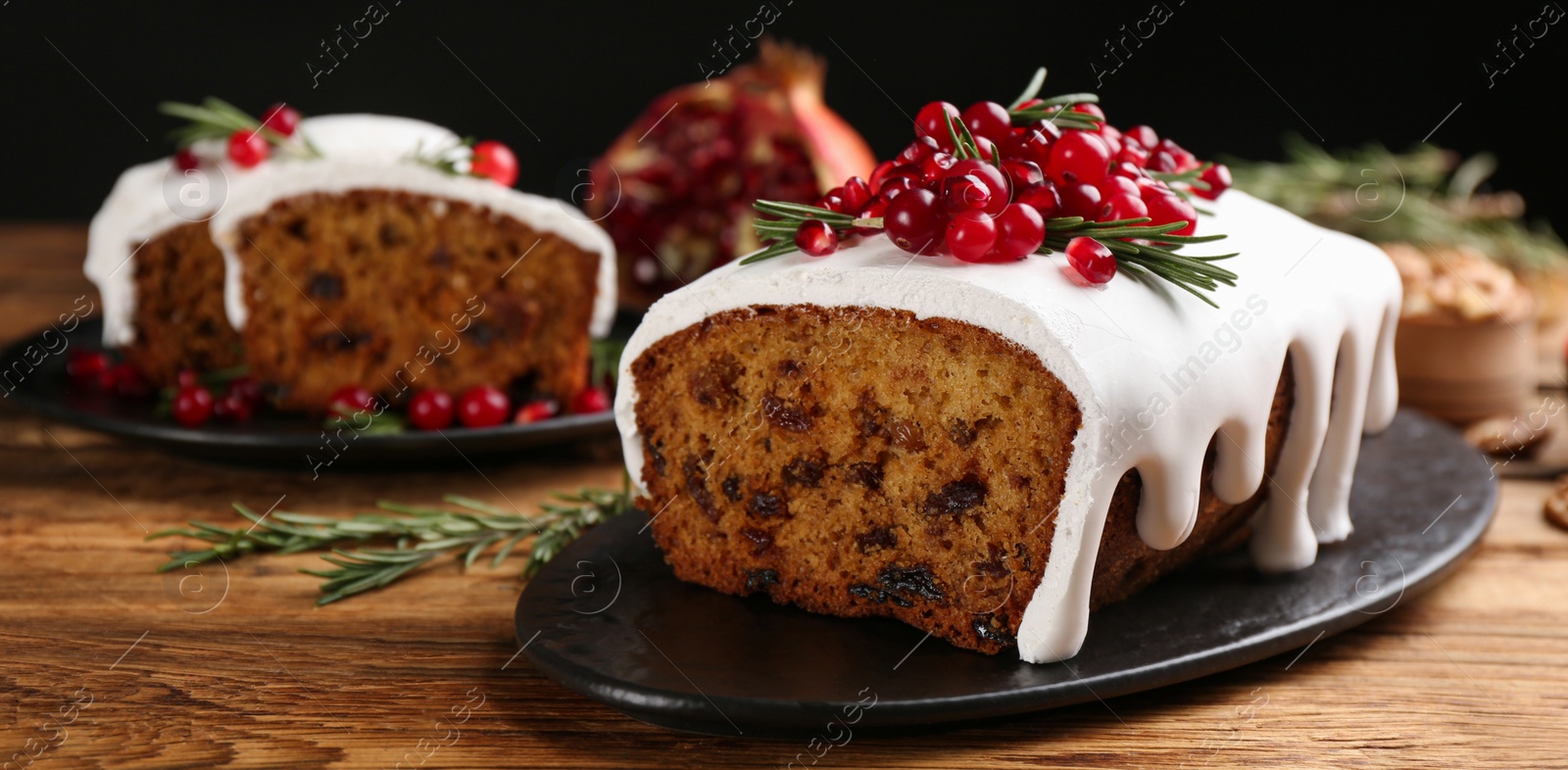 Image of Traditional classic Christmas cake decorated with cranberries, pomegranate seeds and rosemary on wooden table. Banner design 