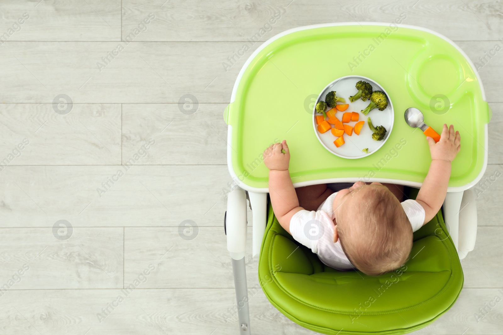 Photo of Cute little baby eating healthy food, top view. Space for text