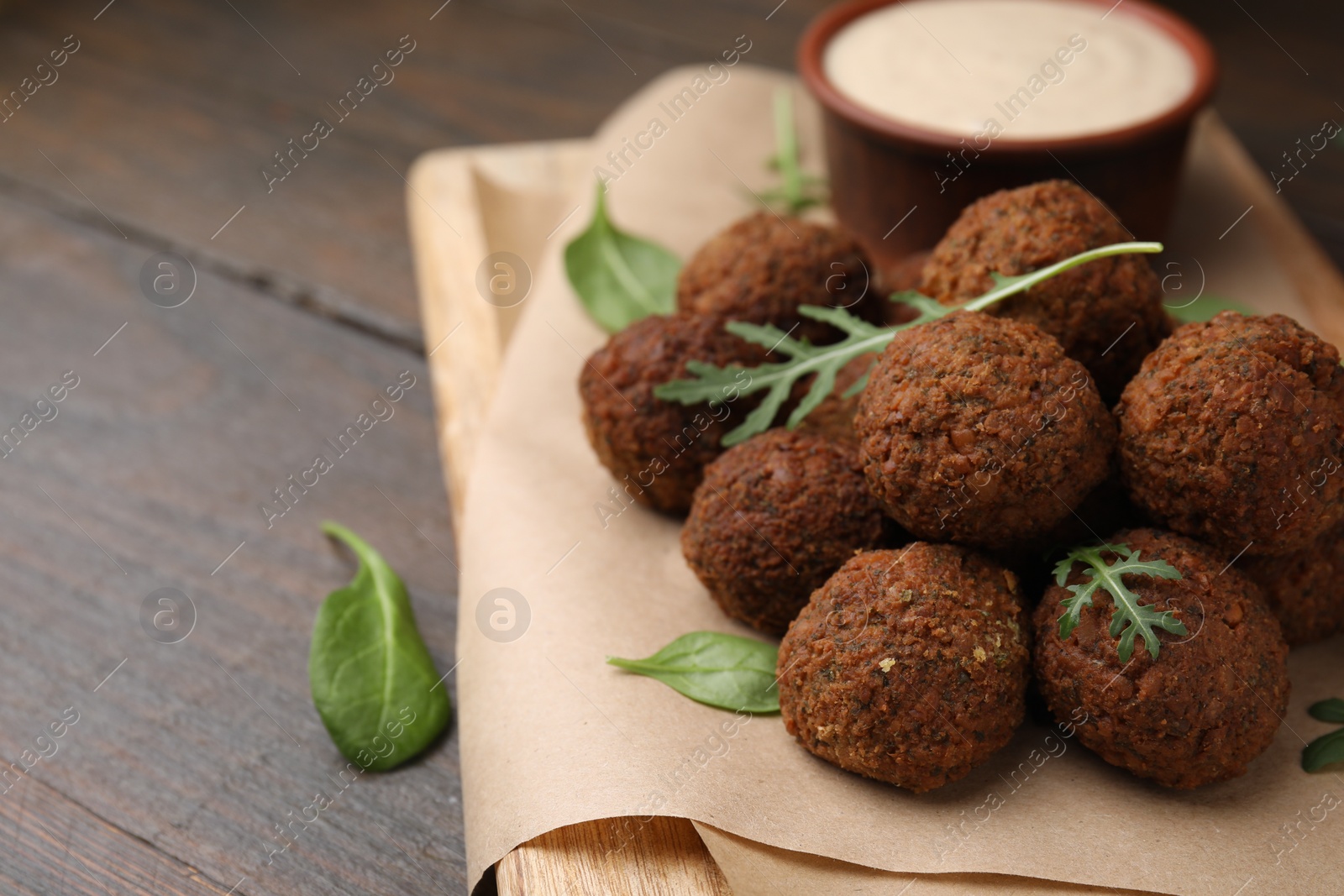 Photo of Delicious falafel balls, arugula and basil on wooden table, space for text