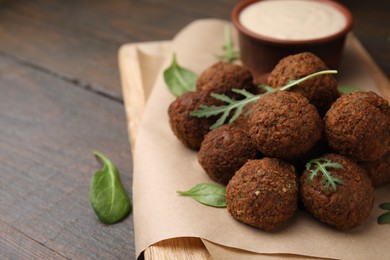 Photo of Delicious falafel balls, arugula and basil on wooden table, space for text