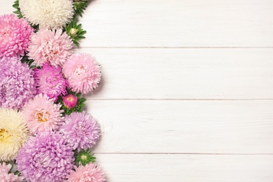 Photo of Beautiful aster flowers and space for text on wooden background, flat lay