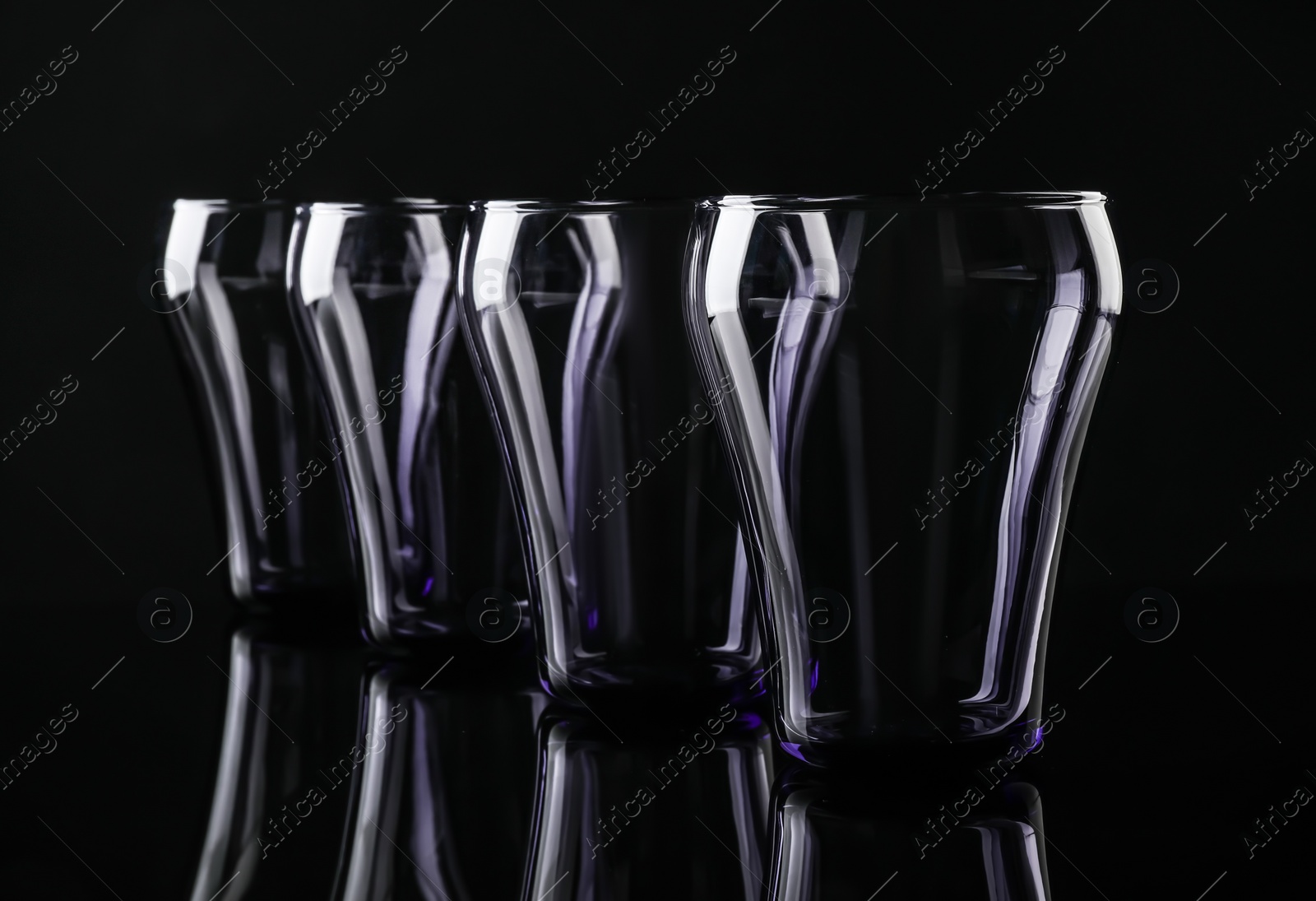 Photo of Set of empty colorful glasses on black background