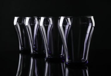 Set of empty colorful glasses on black background