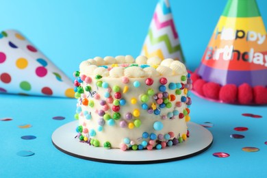 Photo of Cute bento cake with tasty cream and decor on light blue background