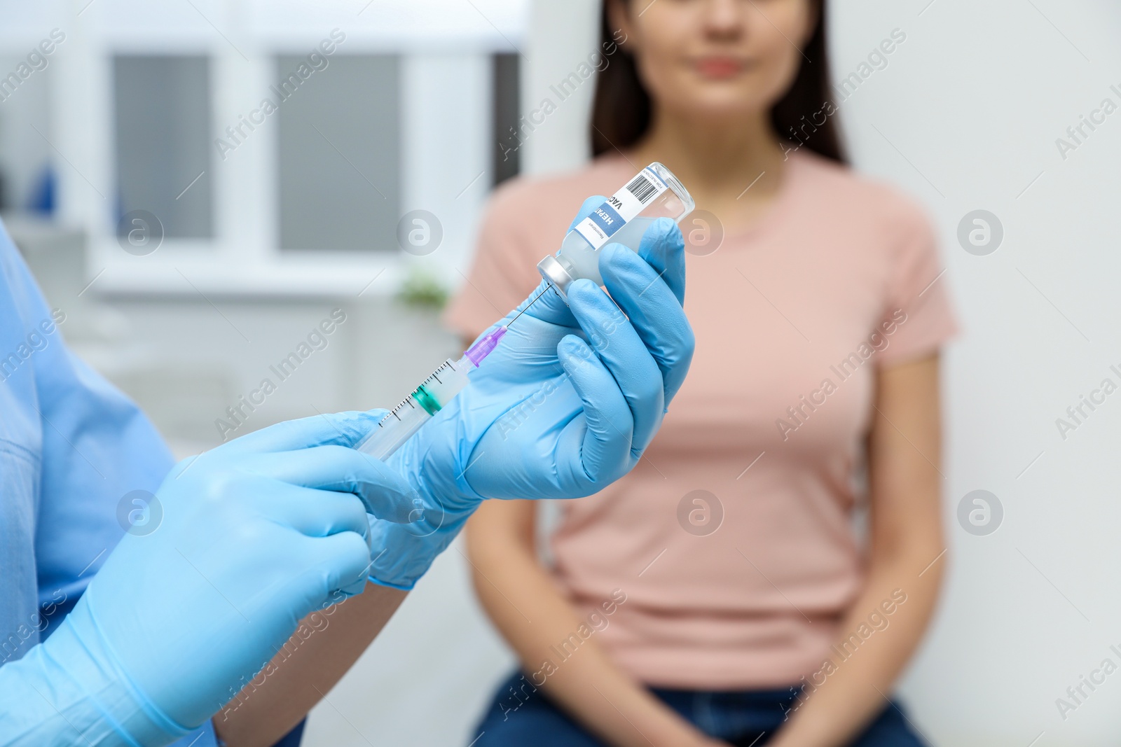 Photo of Woman waiting to get hepatitis vaccine at clinic. Doctor filling syringe from glass vial, closeup